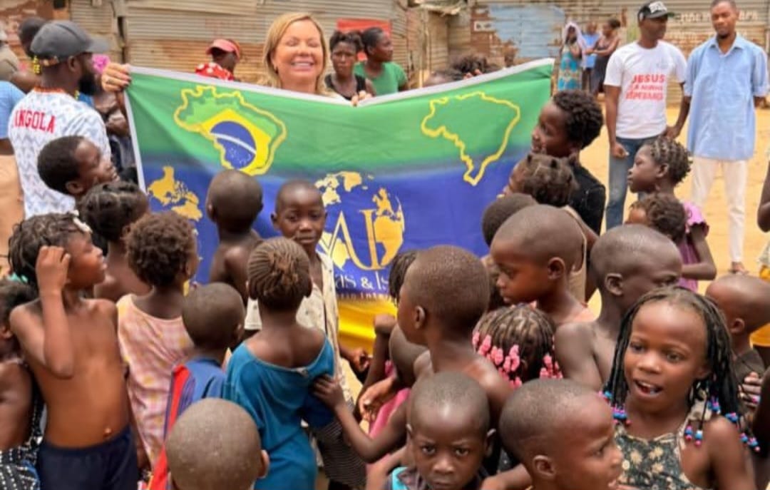 Sandra Martins sorrindo com uma faixa missionária cercada por crianças em Angola